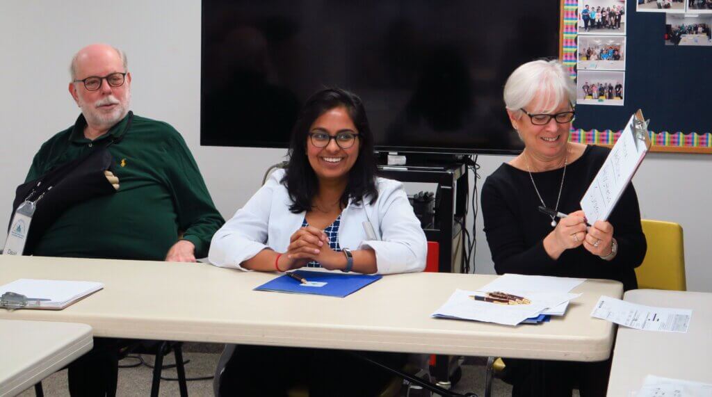 Three people sitting down at a table interacting